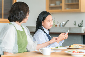 Obraz premium 食事中にスマホを使う反抗期の子供と困る両親・家族 