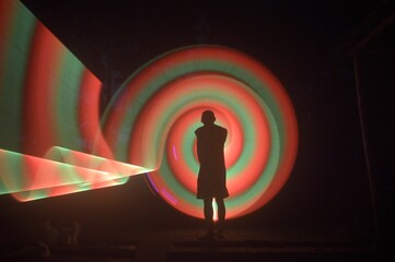 One person standing alone against a Colourful circle light painting as the backdrop