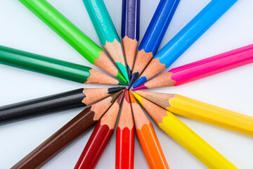 a collection of colored pencils of various colors whose pencil tips are joined together to form a circle on a white isolated background
