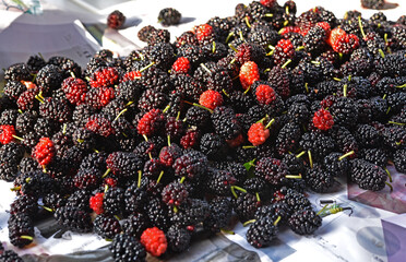 Piles of fresh mulberries on white wooden background.