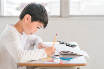 学校・塾・学童の教室で算数のドリルで勉強する小学生の男の子
