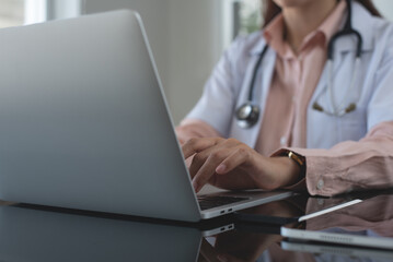 Female doctor working on laptop computer at doctor's office. writing prescripstion, recording...