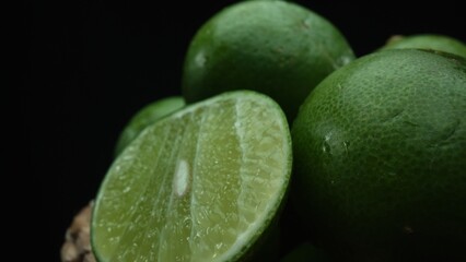 Slices of lime are meticulously arranged in a pile, set against a black background. Each lime slice...