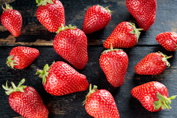 Fresh Red Strawberries Scattered On Dark Wooden Table, Close-Up