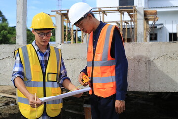 Young professional engineer in hat and blueprint paper is working...At the house construction site. Motivation: success, career growth. achieving goals