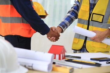 Young professional engineer in hat and blueprint paper is working...At the house construction site. Motivation: success, career growth. achieving goals