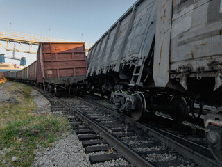 Obraz premium A railway carriage derailed during daylight hours. The wreck of railway wagons. The railway car as a result of the accident came off the rails. Traffic accident on the railway.