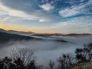 Fog at sunrise between the mountains. Fog in the mountains. Morning fog in the mountains under a blue cloudy sky.