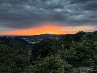 Sunset over the city in the mountains. View of the city at sunset from above. A beautiful sunset over the city buildings from a height.