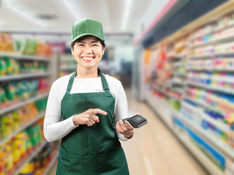 Asian seller wear green apron and green cap smiling with hand holding card reader