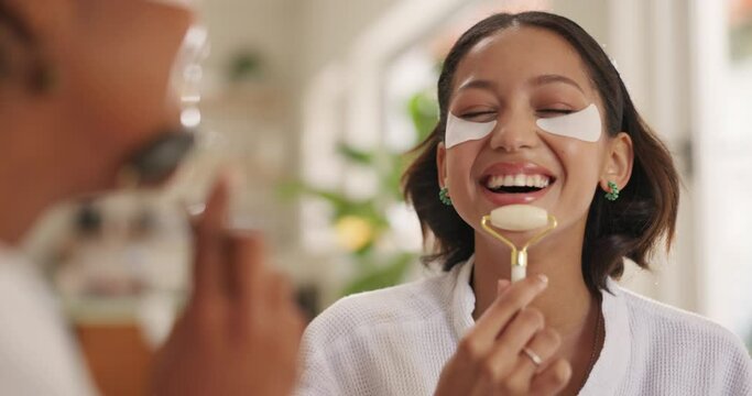 Women, jade roller and together for face, skin or massage with laugh for circulation, health and benefits in home. Girl, people and friends with tools for cosmetics, eye mask or dermatology in house