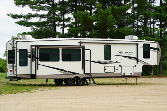 5th wheel campers sit to be sold in a parking lot.