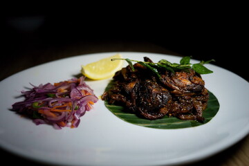 Traditional South Indian Kerala Style beef roast on banana leaf on a white serving plate in the restaurant