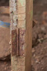 close-up of old rusty metal hinge on wooden pole, reddish brown iron oxide corrodes exposed to moisture and dirt outdoor, blurry background with copy space