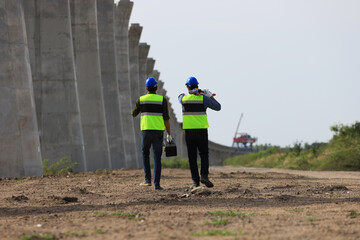 Obraz premium Pile construction: A civil engineer and technician are conducting a survey with a camera along the old railway for the construction of new electric train piles