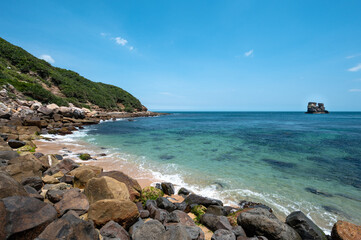 Mystery bay hidden behind the hill, with beautiful beach and rocks on the shore, twin candlesticks islets in the distance, in Jinshan, New Taipei City, Taiwan.
