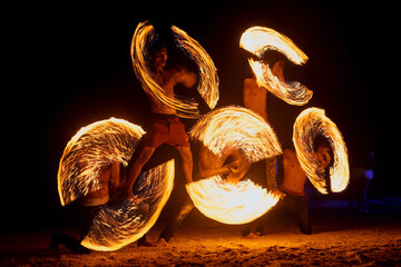 People, fire and dancing on beach with dancers for New Years celebration with smoke and adventure. Performer, light and streak at ocean or Thailand party for long exposure show, art or nightlife