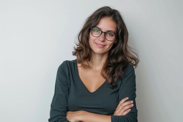 Obraz premium Confident brunette woman in glasses smiling with arms crossed