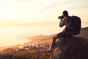 Photography, mountain and man with camera for sunset, memories and adventure with backpack. Professional photographer, outdoor and hiking on cliff with tech, creativity and view of ocean in Brazil