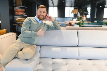 Obraz premium A handsome young man chooses furniture in a store