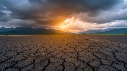 Cracked dry earth under a dramatic sunset with stormy clouds in the background, symbolizing extreme weather and climate change effects.