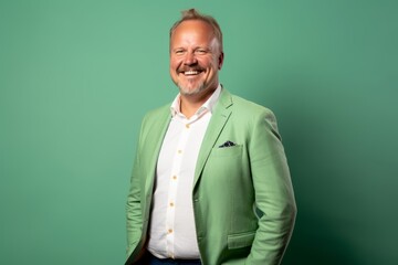 Fototapeta premium Portrait of a happy senior man in a green jacket on a green background.