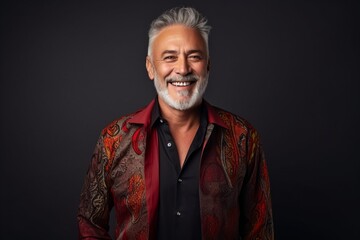 Obraz premium Portrait of a happy senior man in a colorful shirt on a dark background.