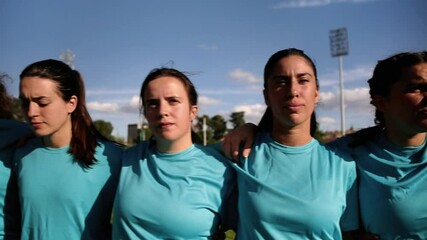 Focused Female Rugby Players in a Huddle. Determined female rugby players in blue jerseys huddling with focused expressions before a game. - Powered by Adobe