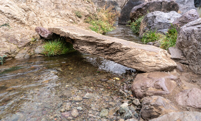 An unsafe bridge made from a single piece of wood on a hiking trail in the mountains of Morocco