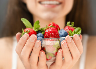 woman holds a plate of berries in her hands and smiles, close-up