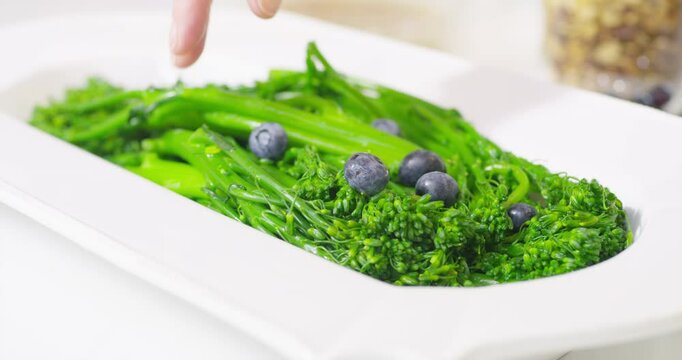 Adding salad dressing to blueberry broccolini salad