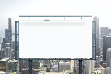 Fototapeta premium Blank white billboard on city buildings background at daytime, front view. Mockup, advertising concept