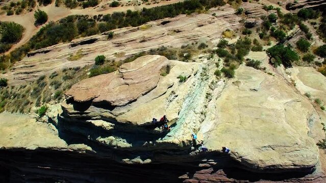 Aerial: Drone Forward Shot Of Tourists On Top Of Vasquez Rocks In Semi Arid Desert - Agua Dulce, California
