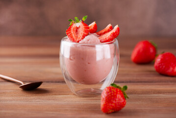 Whipped tofu and strawberry mousse dessert in a glass on a wooden table. Vegan food.