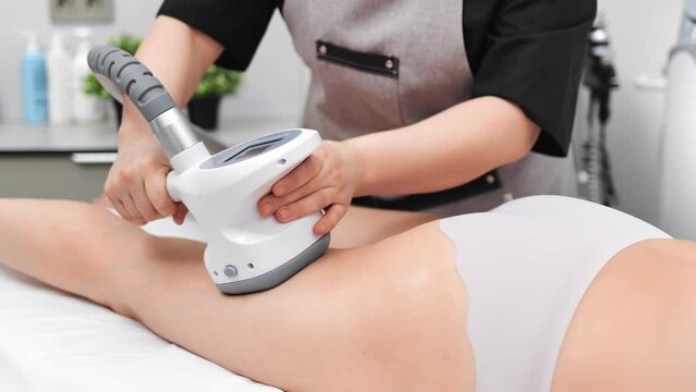 Woman visiting modern beauty salon with anticellulite treatments, masseuse using RF-lifting device