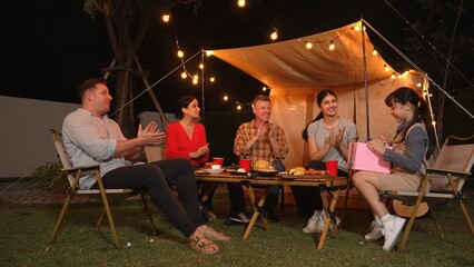 Family together celebrate anniversary in garden. Senior give gift to granddaughter. Outdoor camping...