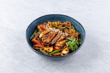 fried Udon with beef and vegetables on dark stone table