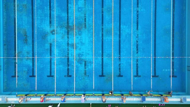 The start of a swimming competition in an outdoor pool: swimmers are diving into the water and beginning to swim