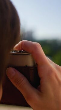 vertical shot. the girl presses the button. a young girl with a camera takes a picture. Fashionable and attractive beautiful woman with an analog film camera in her hands.  travel and vacation.
