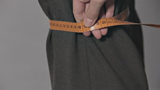 Tailor measuring different parts on a mans body for a suit production. Measures for making men's suits. Textile confection.
