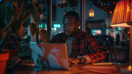 Obraz premium A man works on his laptop in a dimly lit coffee shop