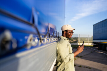 Deliveryman using smart phone at truck stop.