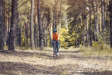 Obraz premium woman cyclist rides in the forest on a bike.