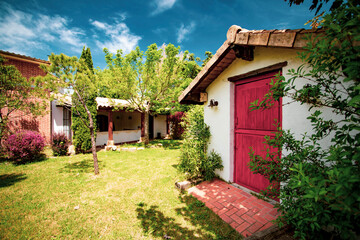 Cute cottage in a fairytale setting surrounded by trees, plants and flowers.