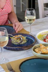 Young woman having dinner in the Mediterranean restaurant. Various dishes served on the table.