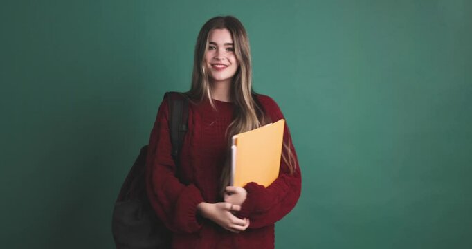 Happy young woman student standing with books