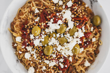 spaghetti noodles with sundried tomatoes green olives and crumbled fetta cheese