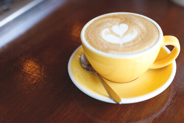 hot coffee cup latte art with spoon Serve ready to drink in cafe on wooden table coffee shop.  Leave copy space empty to write the side text. soft focus.
