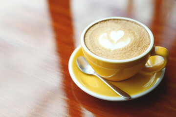 hot coffee cup latte art with spoon Serve ready to drink in cafe on wooden table coffee shop.  Leave copy space empty to write the side text. soft focus.