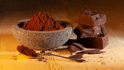 dark chocolate and bowl with cocoa powder, on wood..